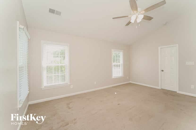 a clean empty room with a ceiling fan and a window
