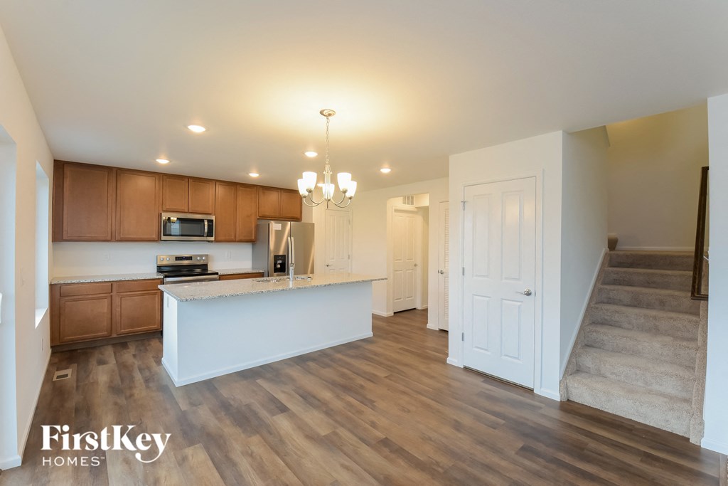 an open kitchen and living room with wood flooring and a staircase