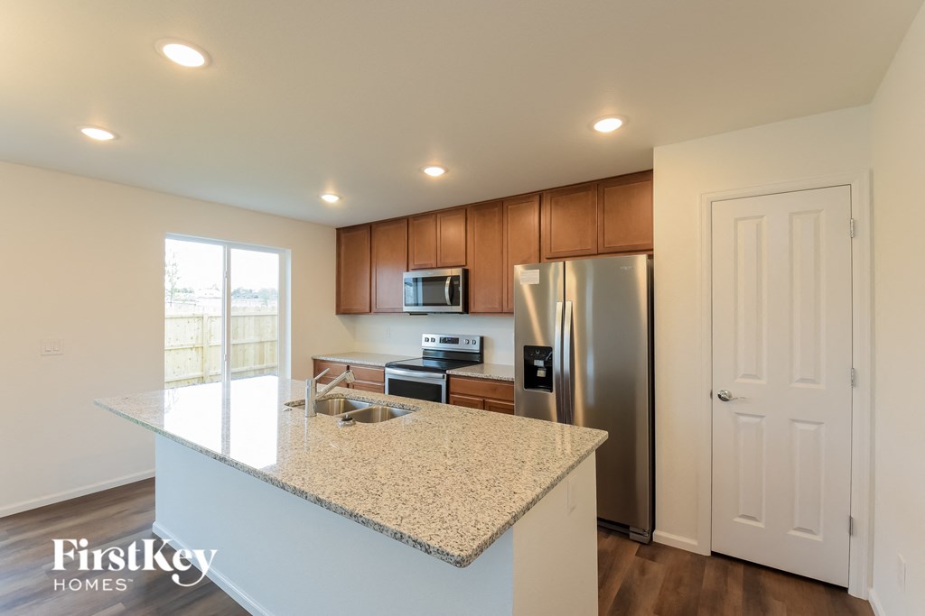a kitchen with a granite counter top and a stainless steel refrigerator