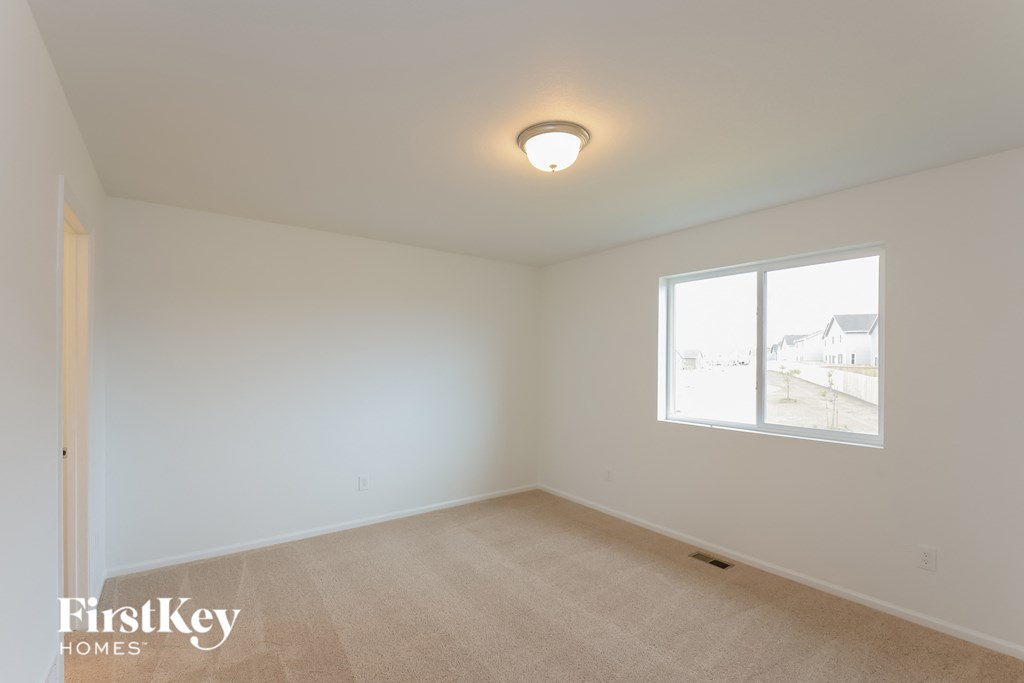 a bedroom with white walls and a large window