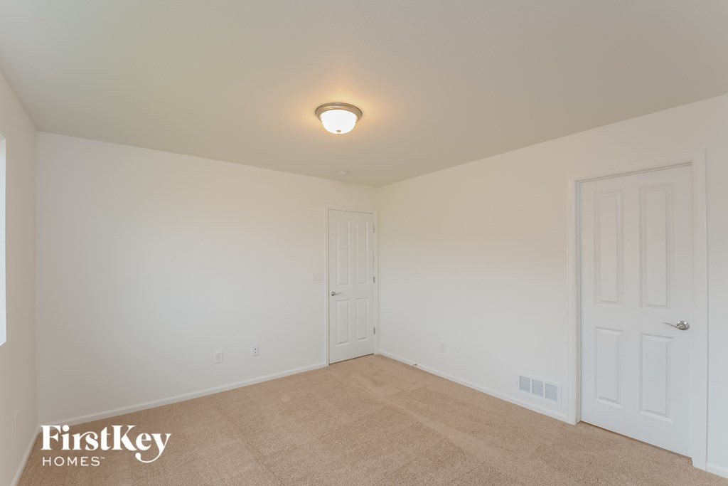 a bedroom with white walls and carpet and a white door