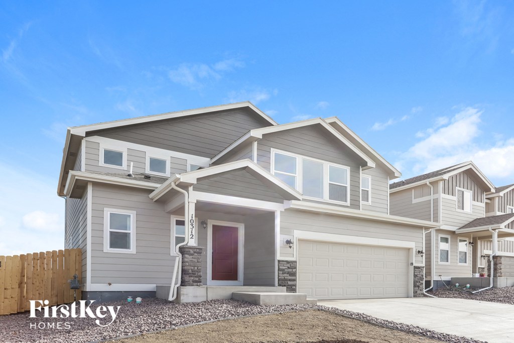 a beige house with a garage door and a blue sky