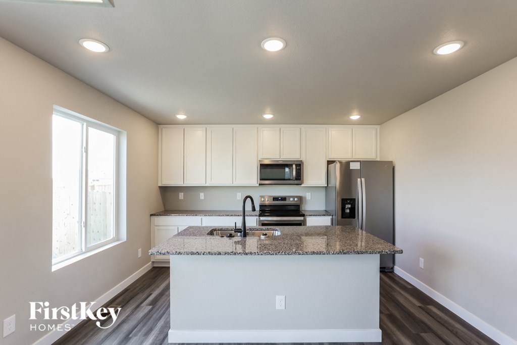 a kitchen with a granite counter top and a stainless steel refrigerator
