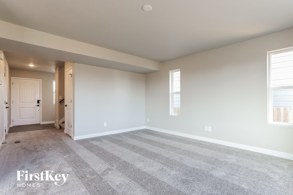 a living room with carpet and a door to a hallway