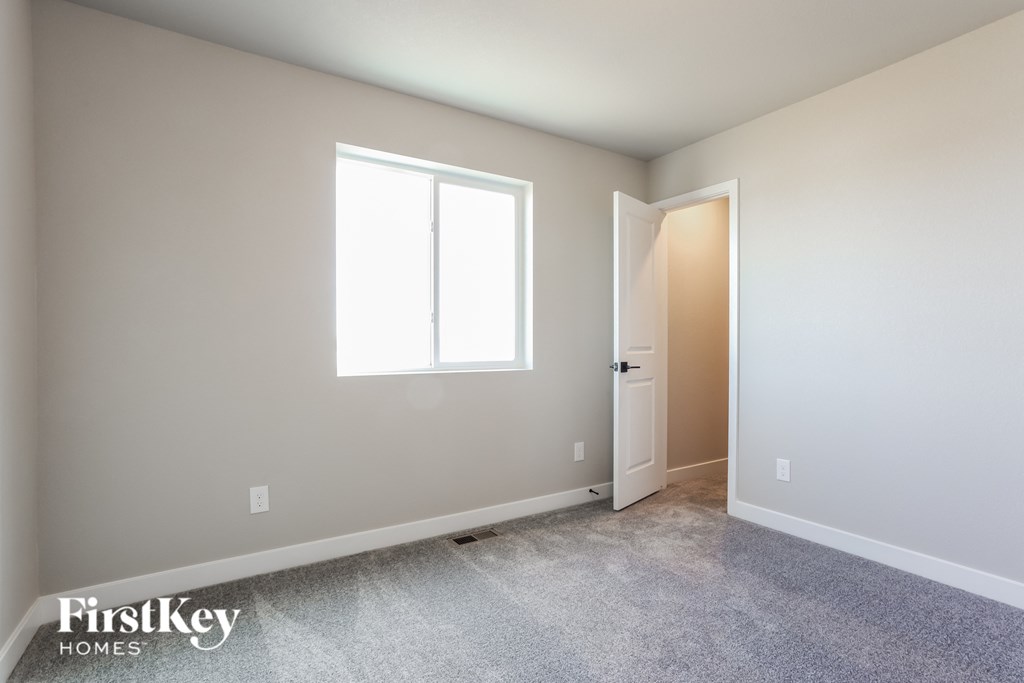 a bedroom with a door and a window and a carpeted floor