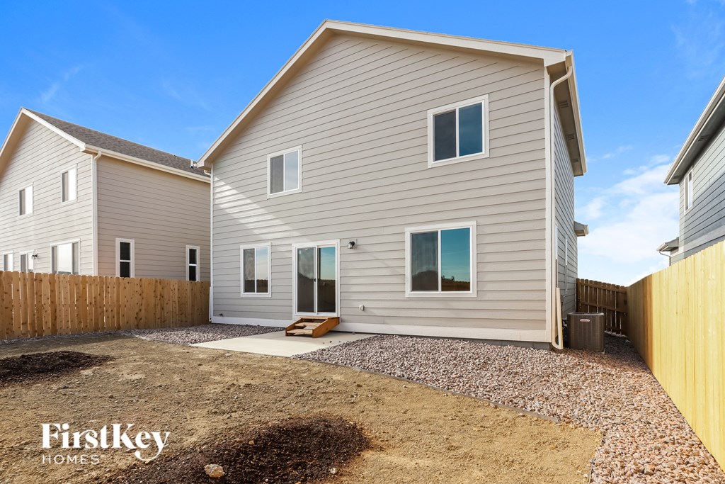 a backyard with a white house and a wooden fence