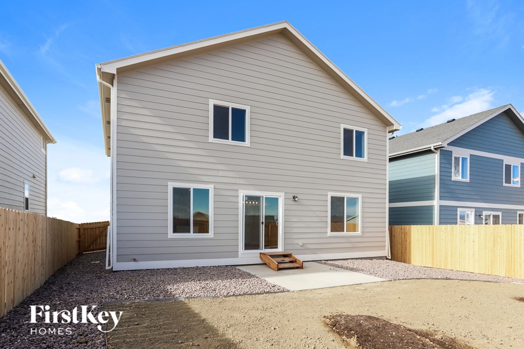 a gray house with a gravel driveway and a wooden fence