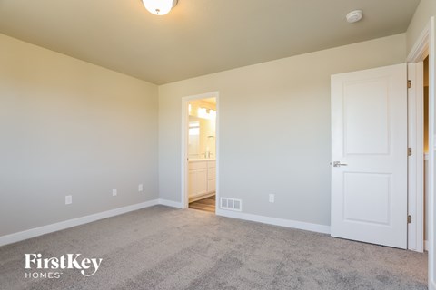 a bedroom with a carpeted floor and a door to a bathroom
