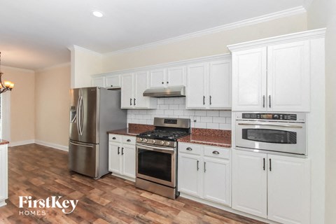 A kitchen with white cabinets and a stainless steel refrigerator.