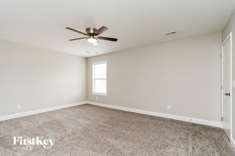 the spacious living room with ceiling fan and carpet