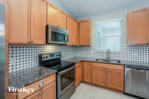 A kitchen with wooden cabinets and a black and white tiled backsplash.