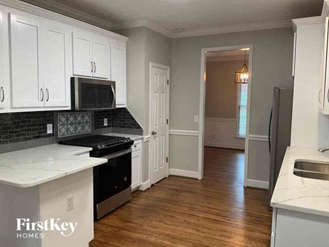 A kitchen with wooden floors and white cabinets.