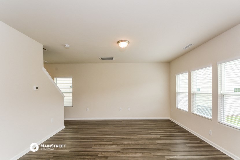 the spacious living room with wood flooring and large windows