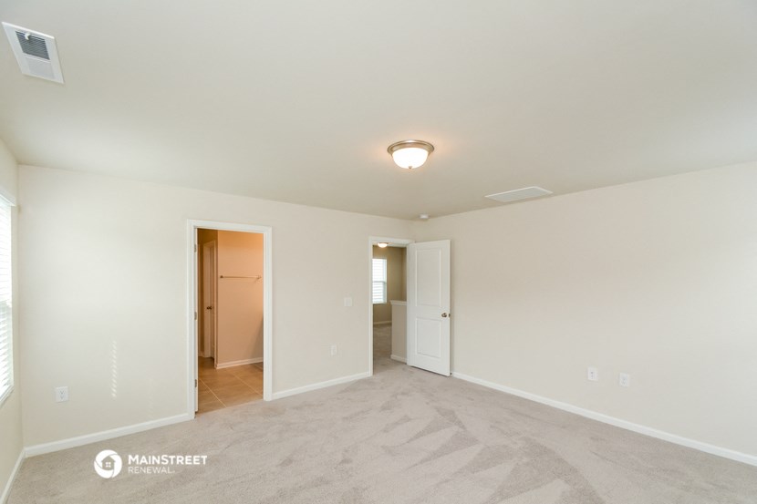the spacious living room with carpeting and white walls