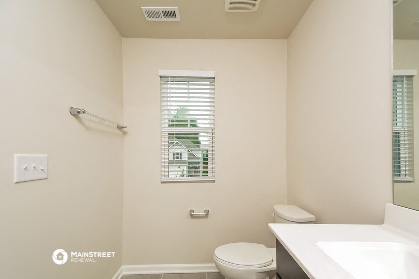 a bathroom with a toilet and a sink and a window