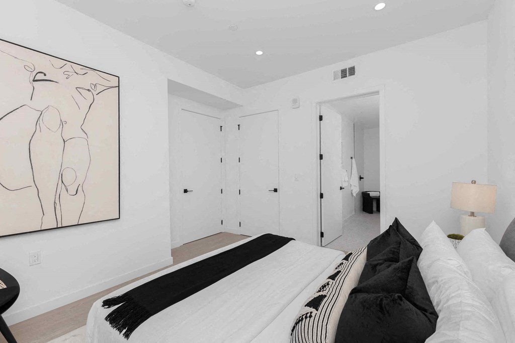 a white bedroom with a bed and a painting on the wall