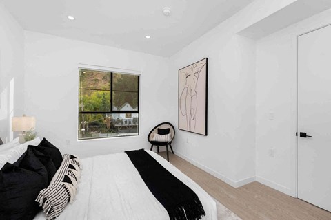 a white bedroom with a bed and a window