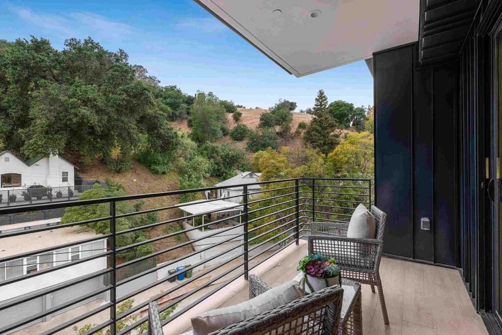a balcony with a table and two chairs and a view of a yard and trees