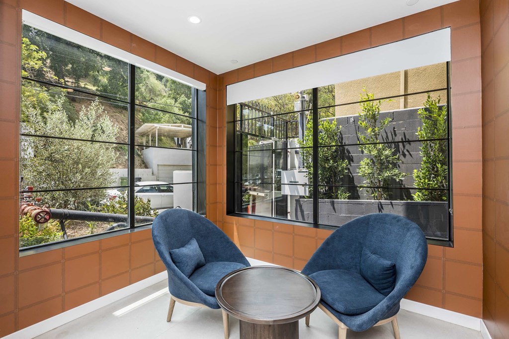 a living room with blue chairs and large windows