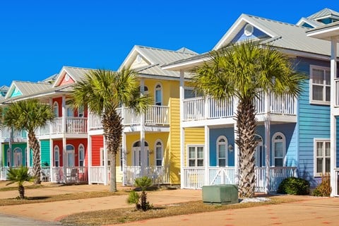 a row of colorful houses with palm trees in front of them