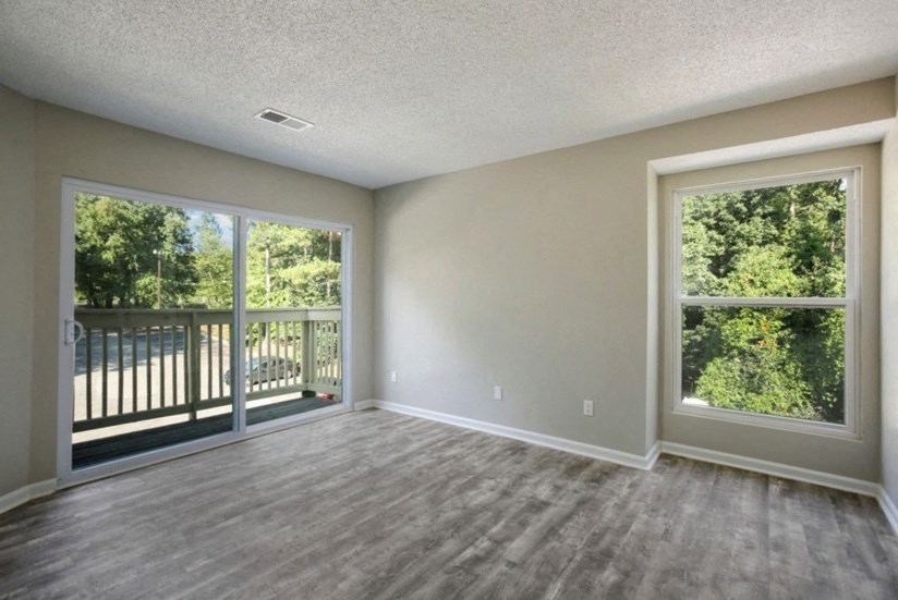 an empty living room with large windows and a balcony