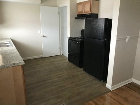 A black refrigerator sits in a kitchen next to a white door.
