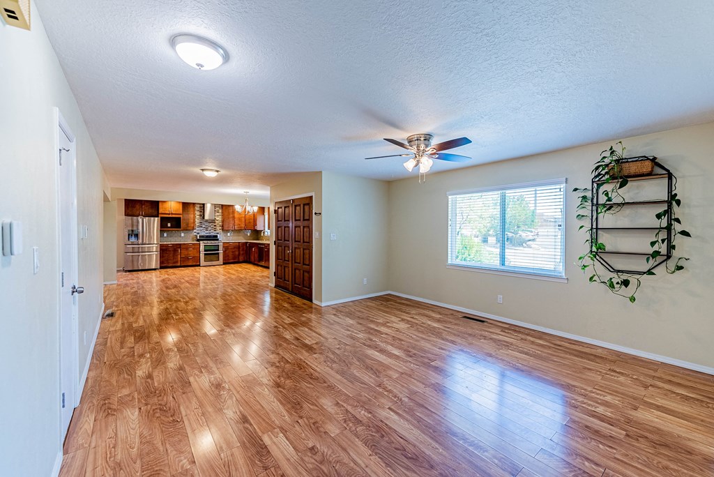 an empty living room with wood floors and a ceiling fan