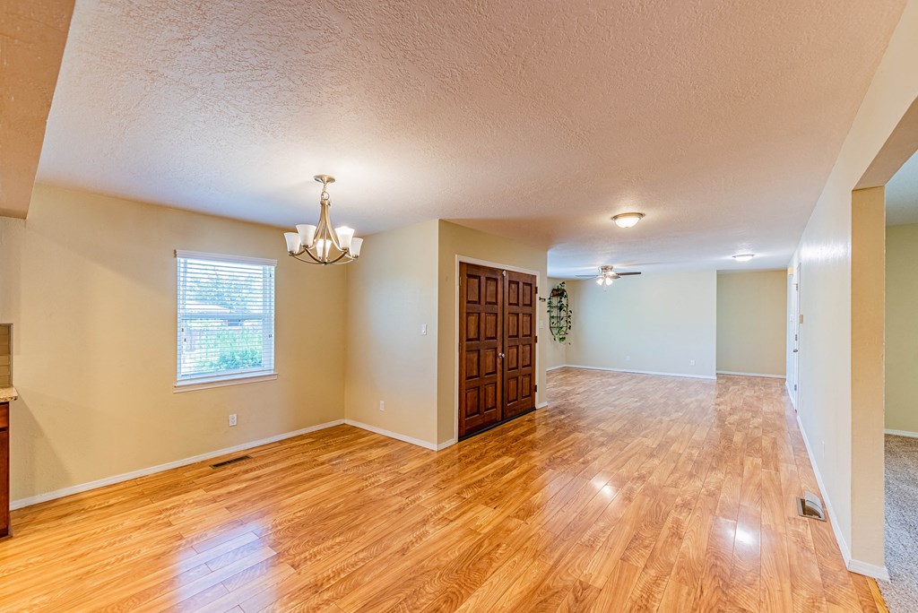 the living room and dining room of an empty house with wood flooring