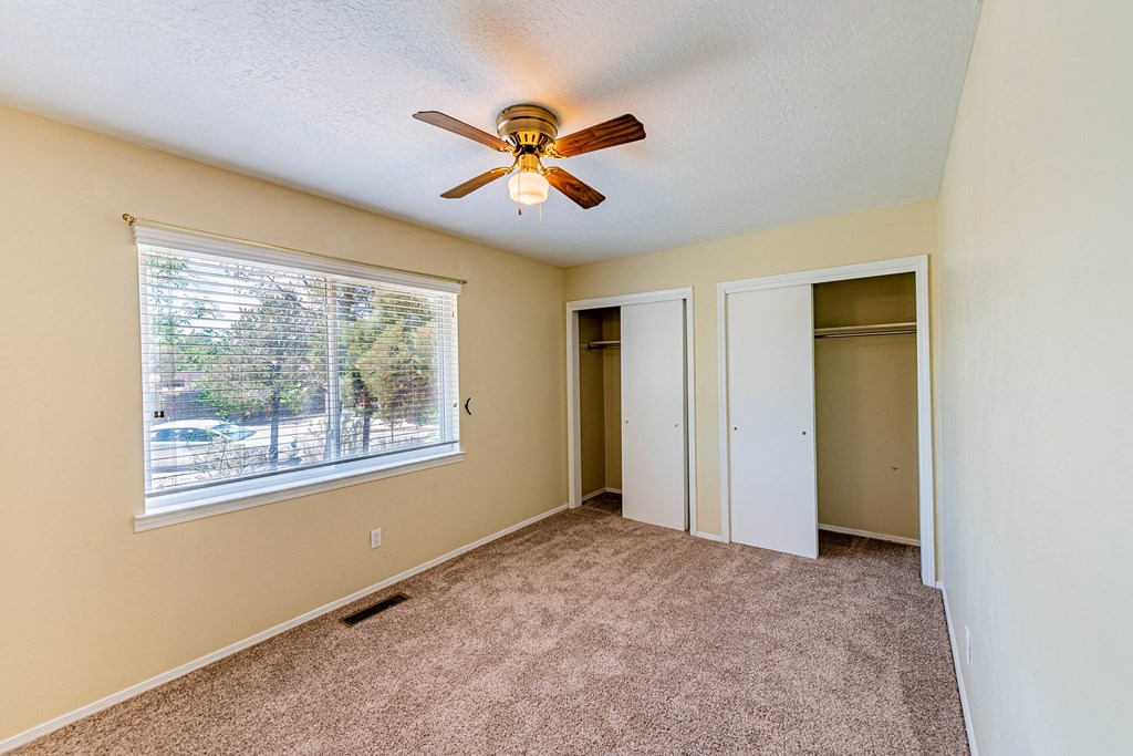an empty living room with a ceiling fan and a window