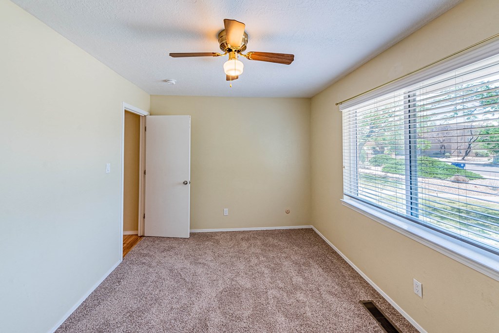 an empty room with a large window and a ceiling fan