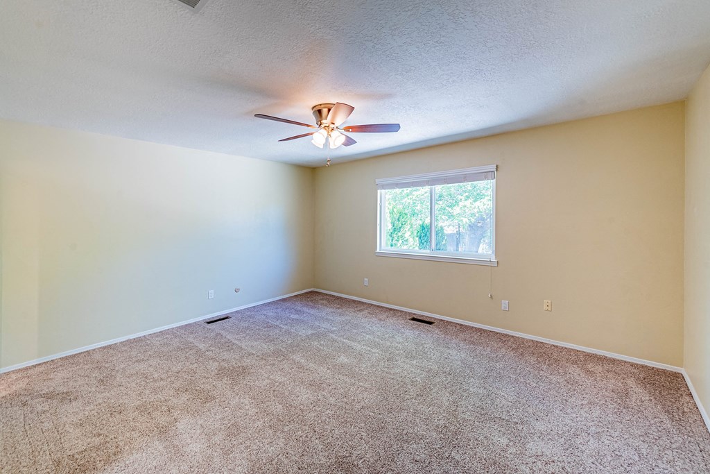 an empty living room with a ceiling fan and a window