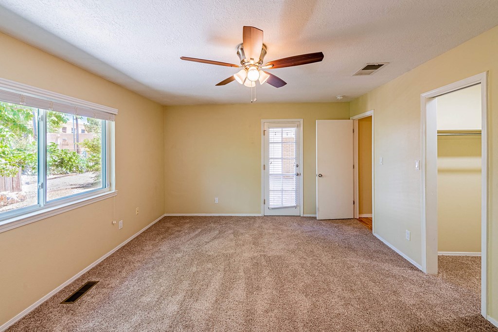 an empty living room with a ceiling fan and a window