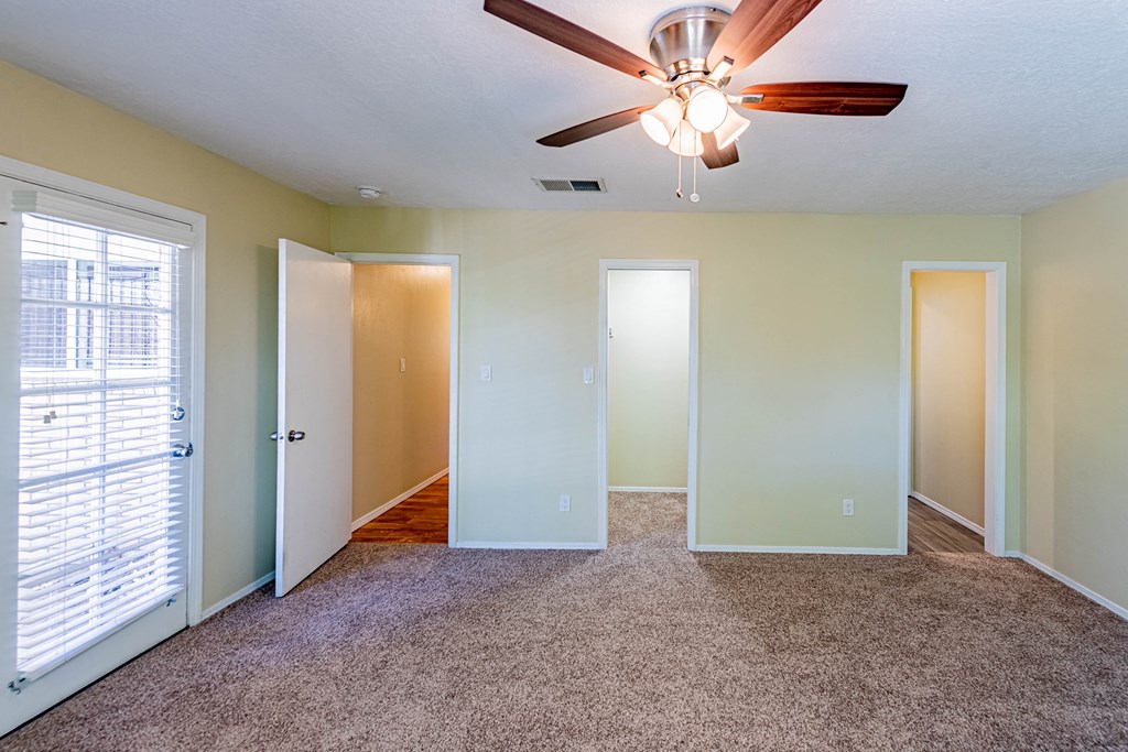 the living room of an empty home with a ceiling fan