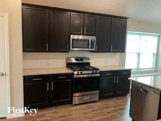 a kitchen with black cabinets and a stove and a microwave