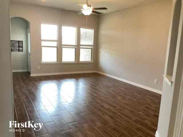an empty living room with wood floors and a ceiling fan