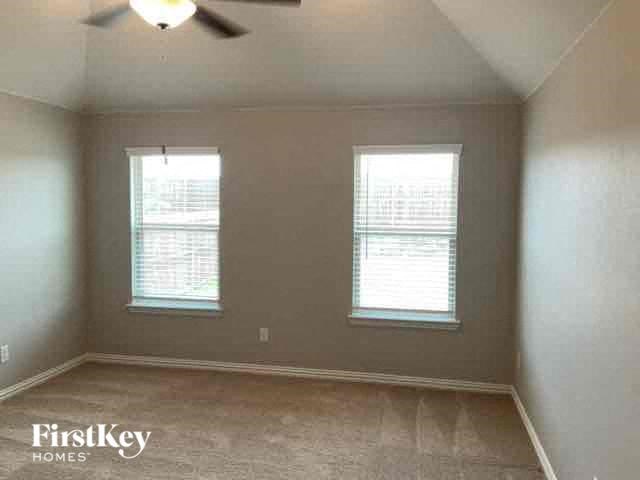 an empty room with two windows and a ceiling fan