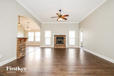 A spacious room with a fireplace and a ceiling fan.