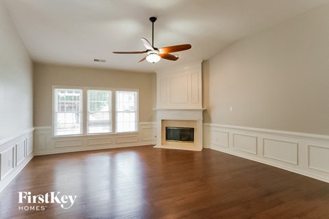 an empty living room with a fireplace and a ceiling fan