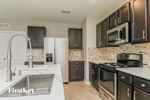 A kitchen with a white sink and black cabinets.