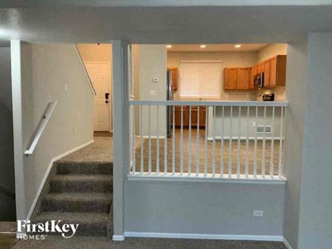 A staircase with a railing leads to a living room.