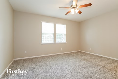 a spacious living room with carpet and a ceiling fan