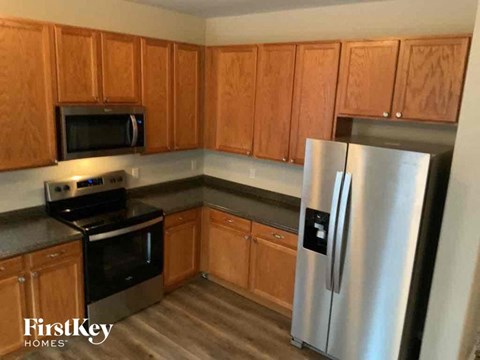 A kitchen with wooden cabinets and a stainless steel refrigerator.