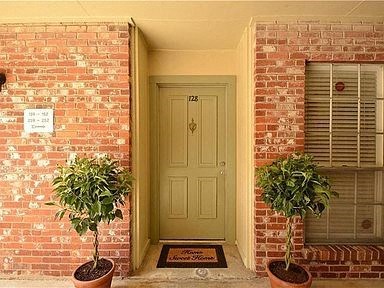 the front door of a brick house with two potted plants