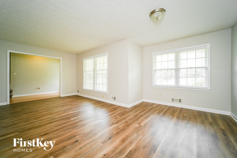 an empty living room with wood floors and white walls