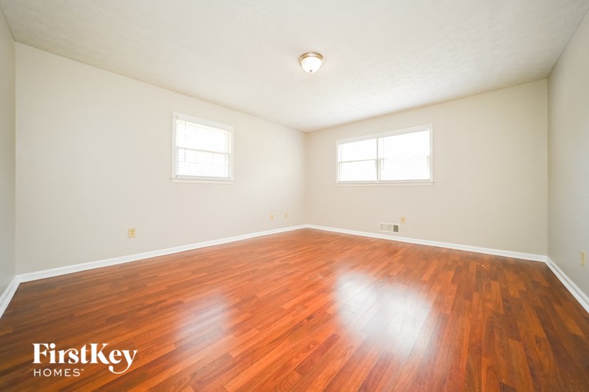the spacious living room with hardwood floors and two windows