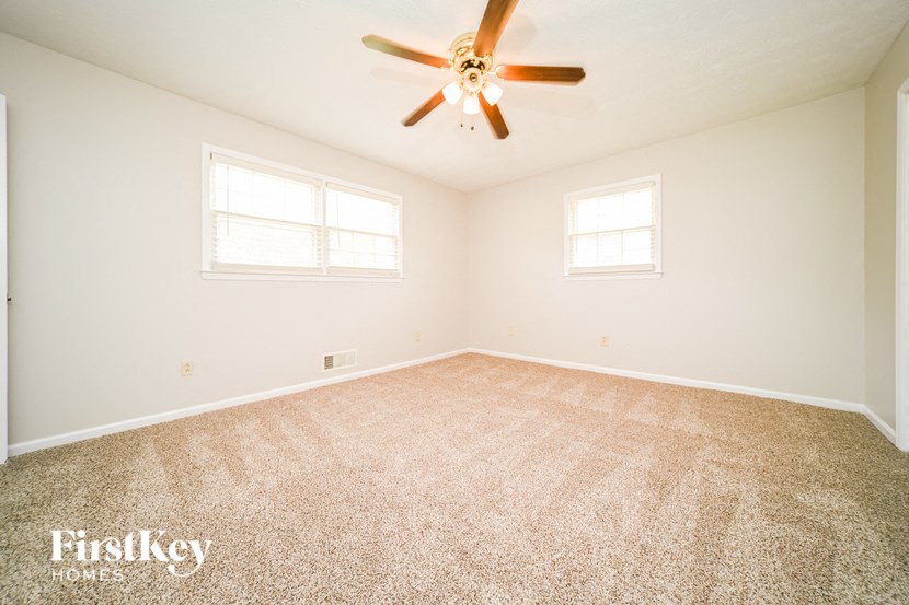a spacious living room with carpet and a ceiling fan