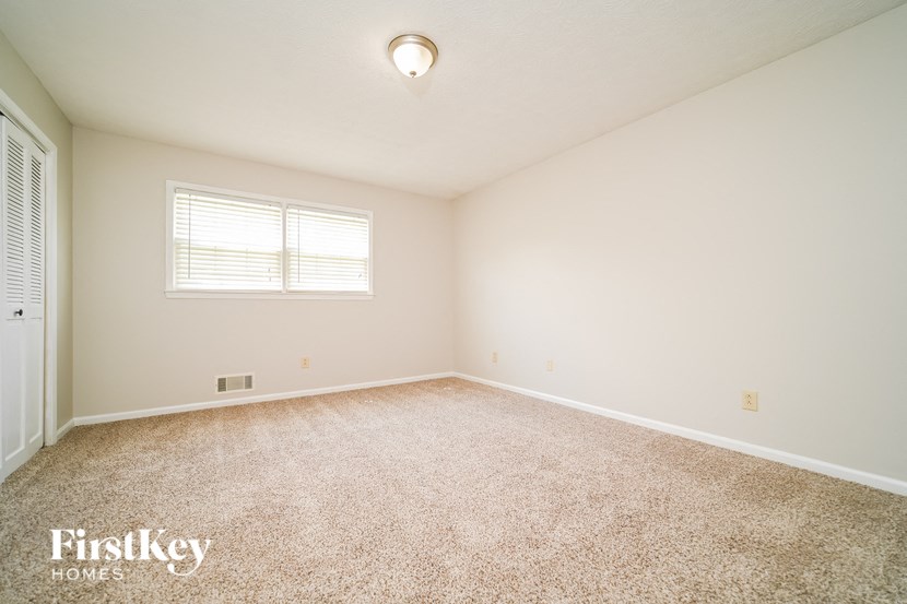 a spacious living room with carpet and a window