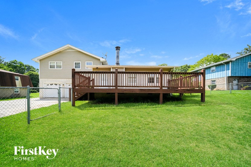 a deck with a privacy fence and a house in the background