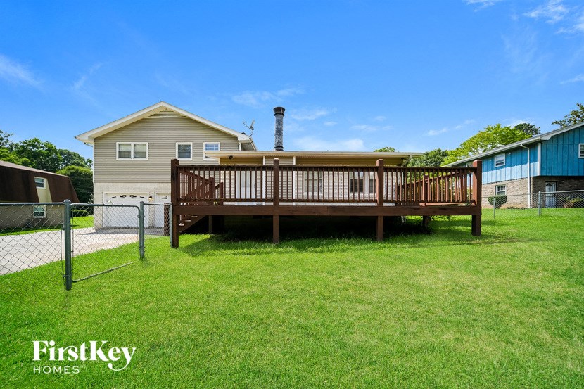 a deck with a privacy fence and a house in the background