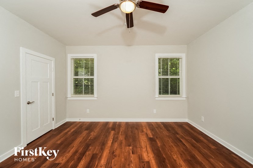 an empty bedroom with a ceiling fan and wood floors